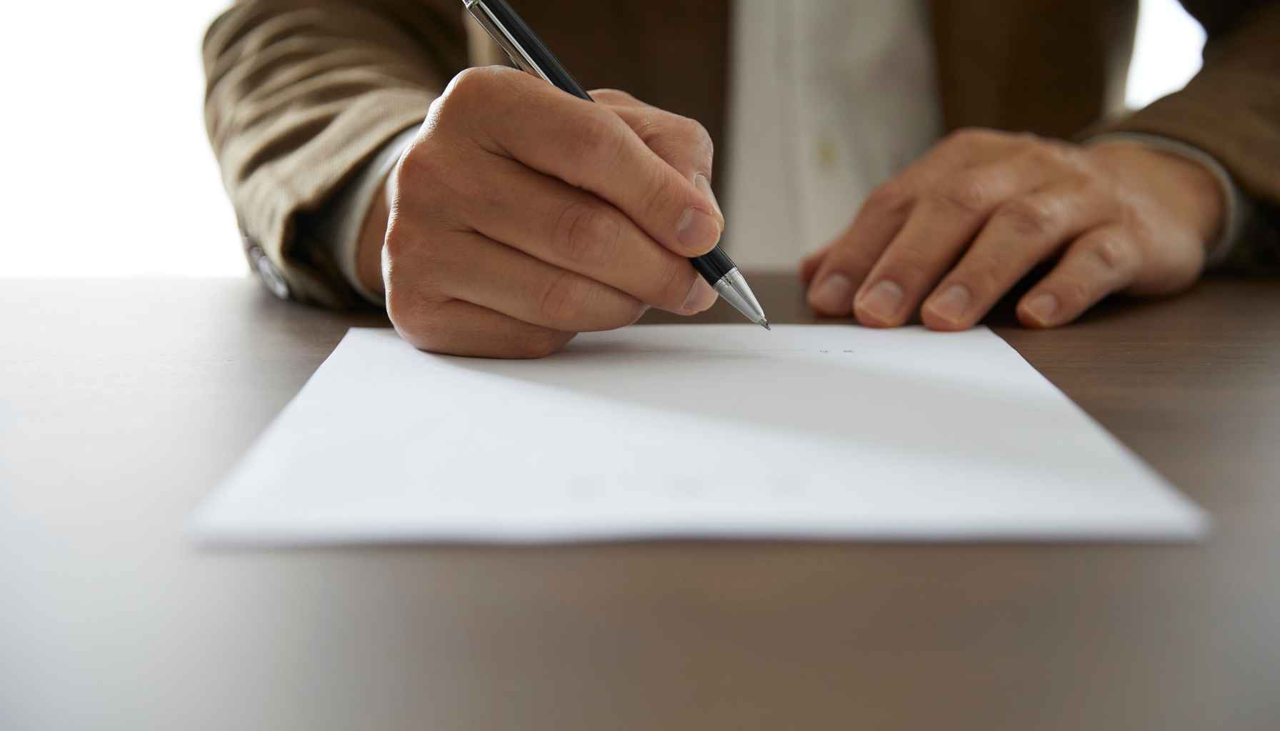 Man writing on paper with pen